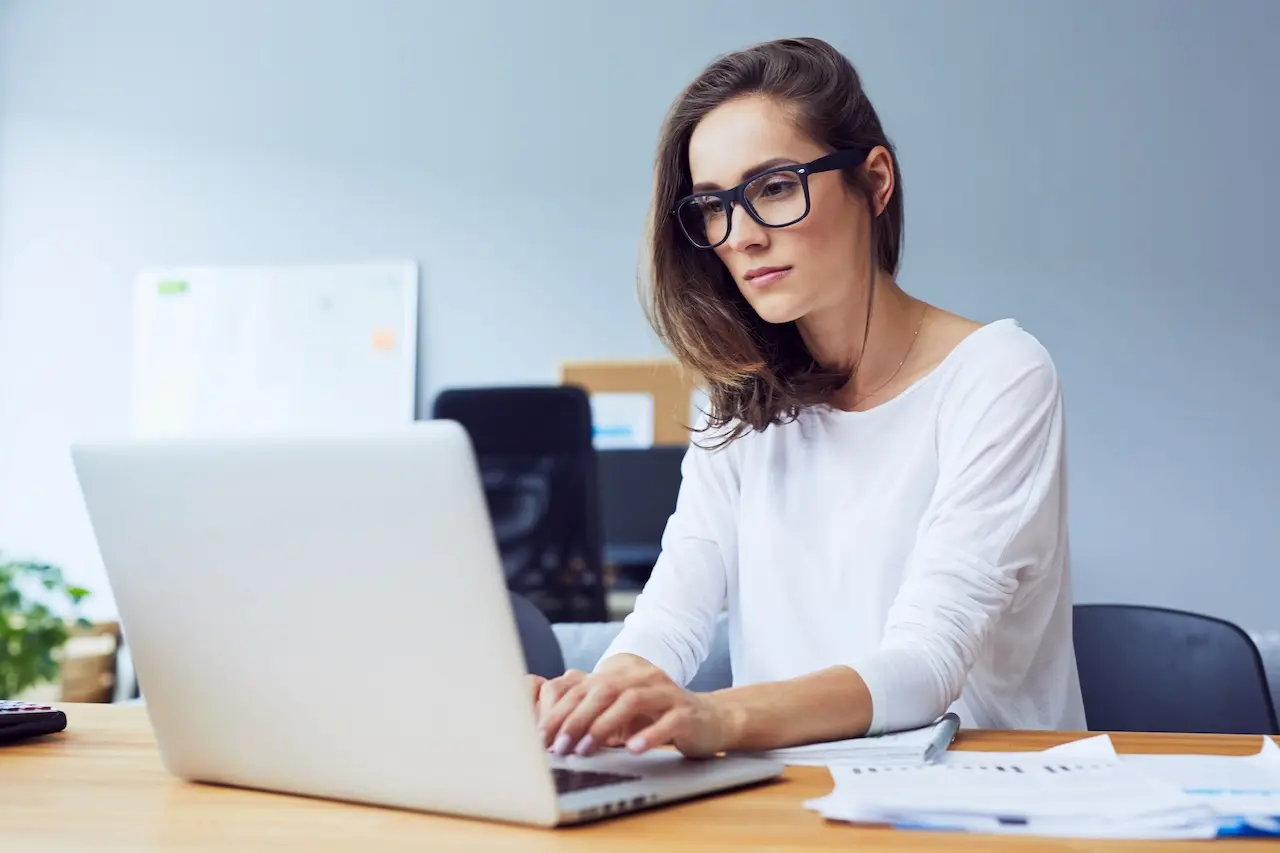 Woman typing on her laptop wearing eye glasses