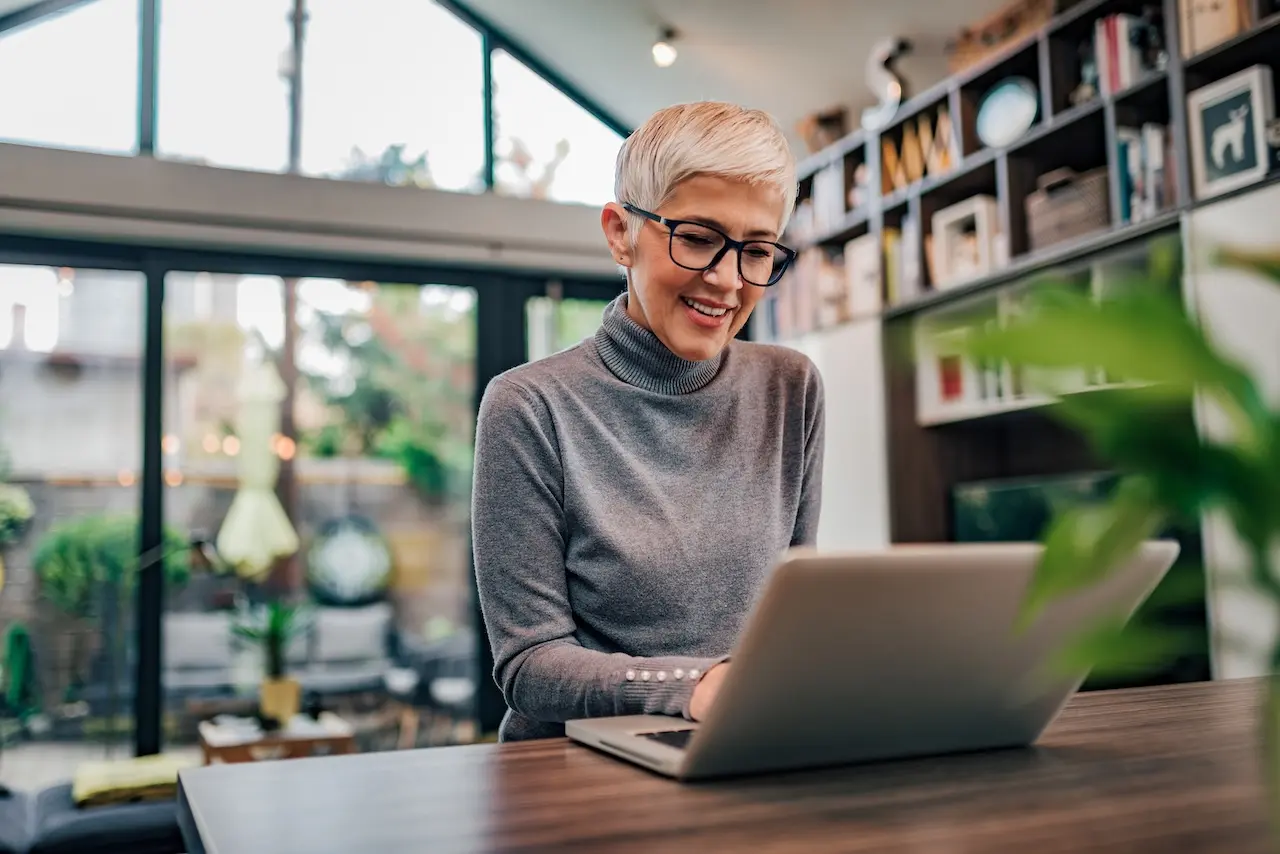 Woman looking at her laptop in her home office