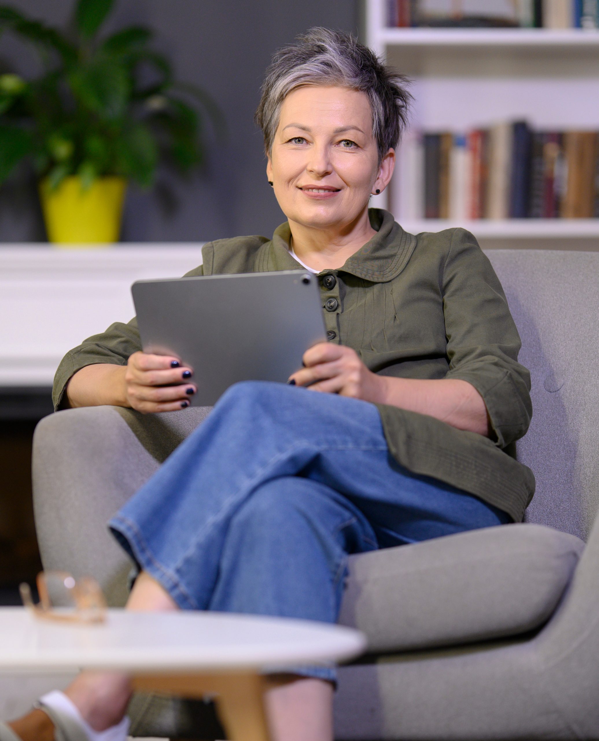 Portrait of smiling mature woman with digital tablet sitting in armchair working online from home because her annapolis seo is on track
