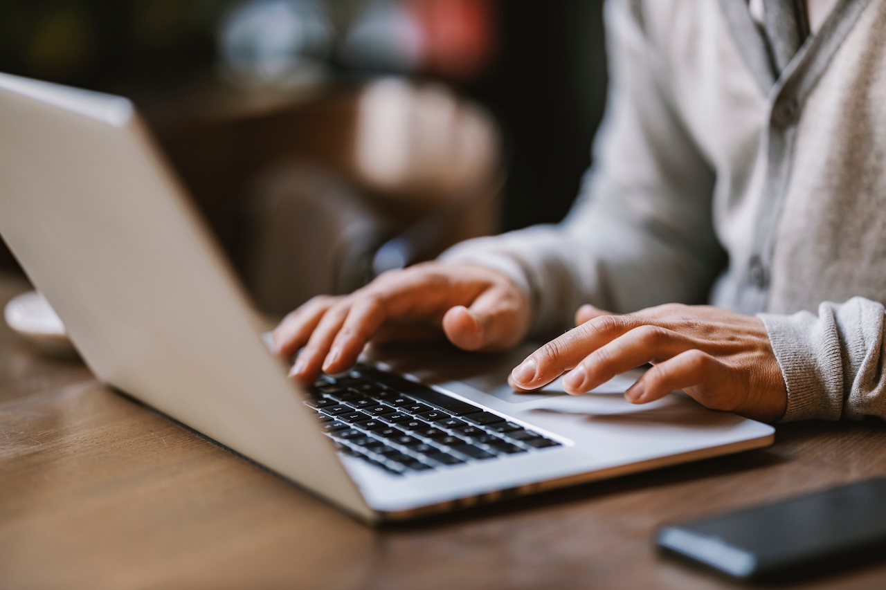 | crownsville media - seo, ai visibility & digital marketing for small business owners Close up of hands typing on a laptop in coffee shop attempting to do content creation with an seo touch